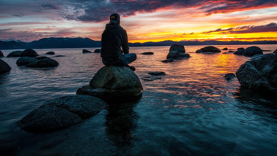 person sitting on rock on body of water 1478685
