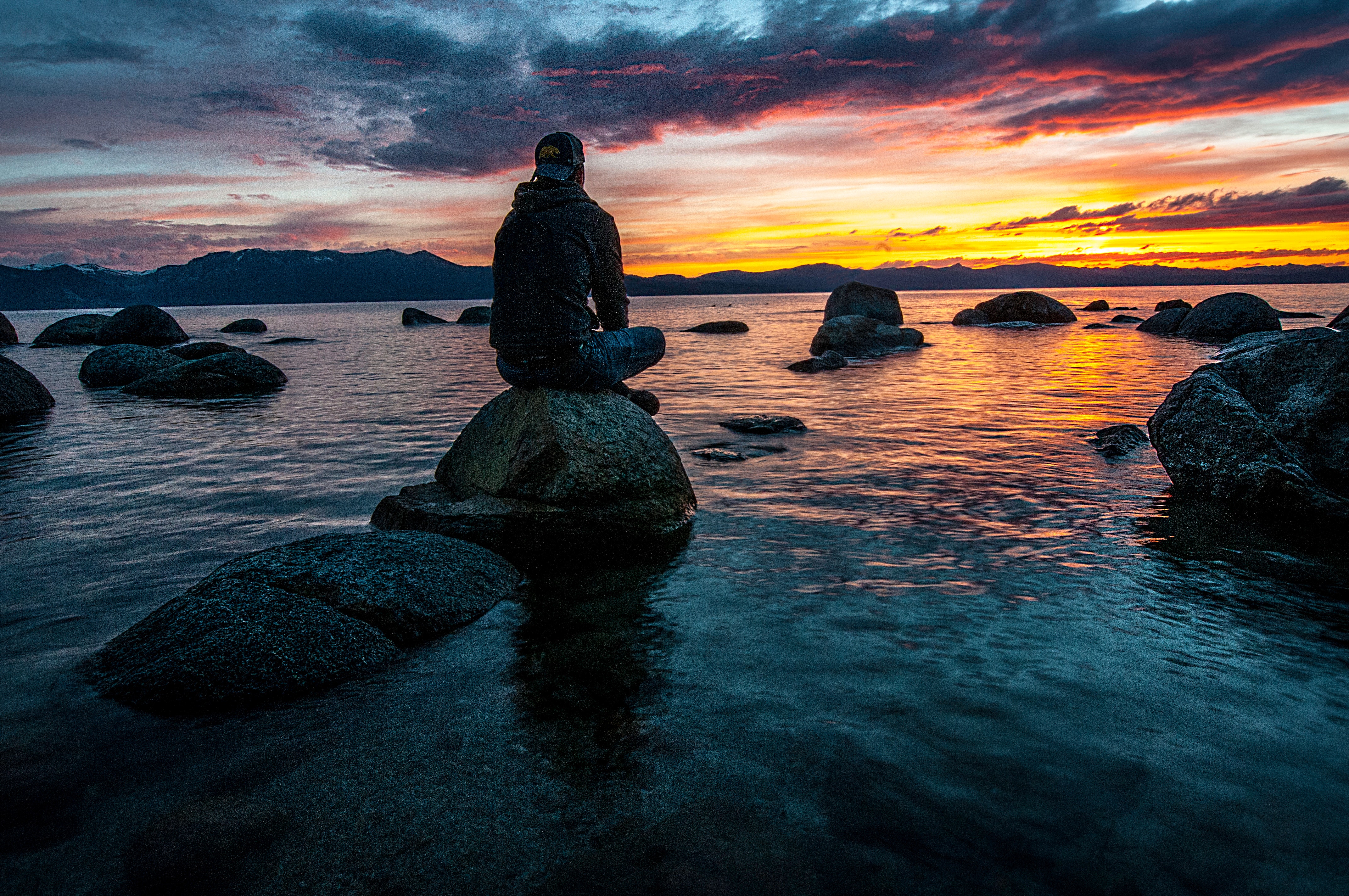 person sitting on rock on body of water 1478685