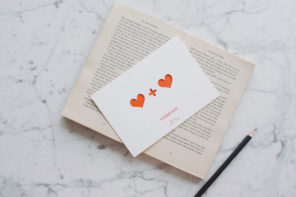opened book with pencil and romantic postcard on marble 3847636