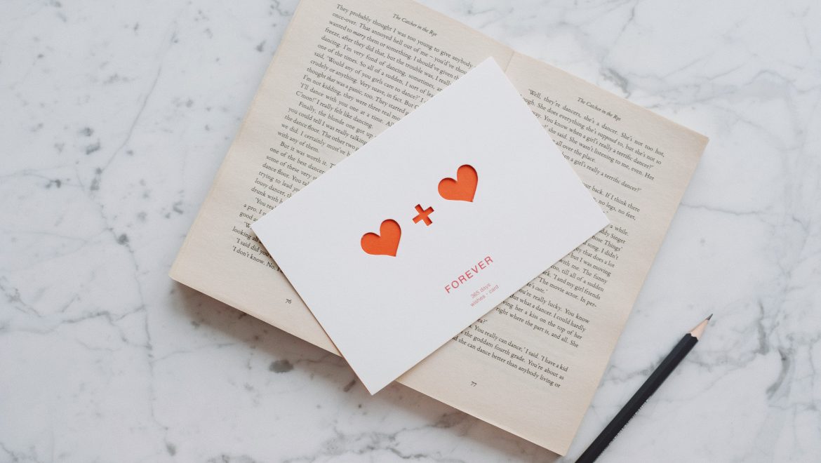 opened book with pencil and romantic postcard on marble 3847636