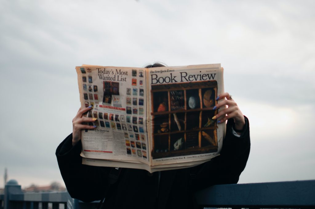person holding white and brown newspaper 3957616