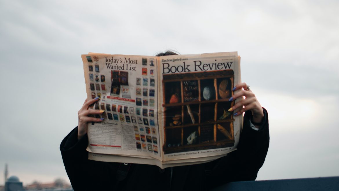 person holding white and brown newspaper 3957616